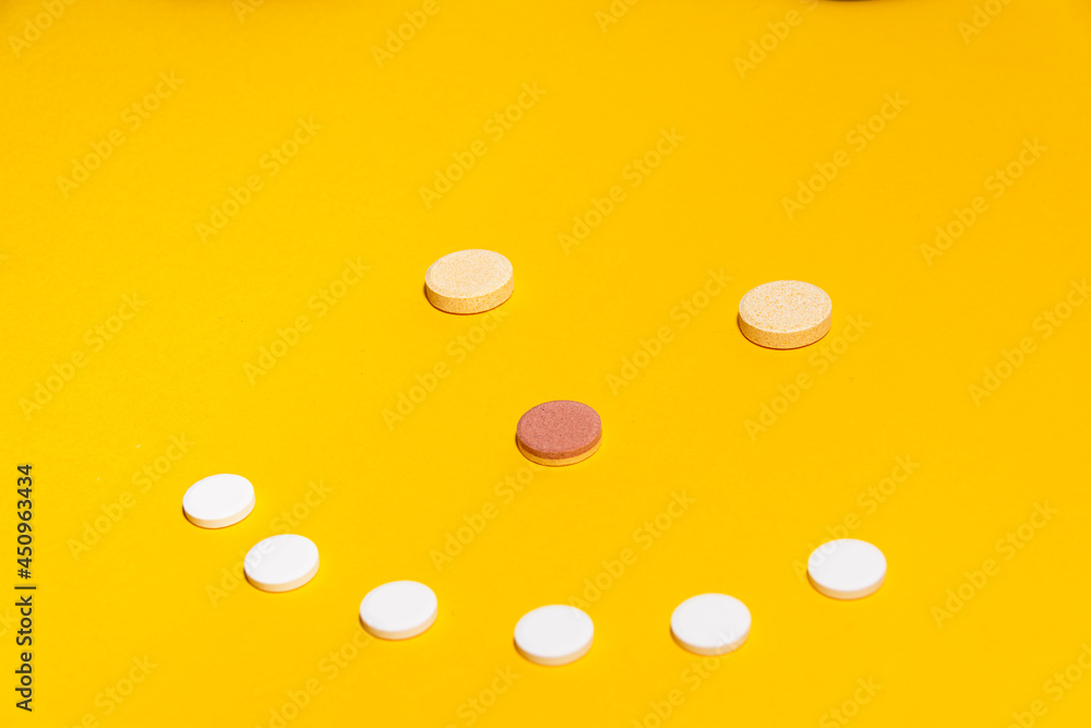 Some vitamin tablets agenced in a smiley face on a yellow background Some vitamin tablets agenced in a smiley face on a yellow background