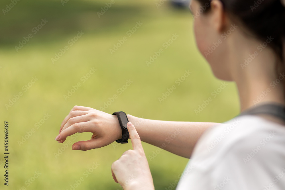 Young woman checks her smart watch. Close up of hand with device. The concept of a modern device and wellness