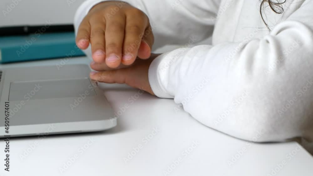 A child girl on distance learning sits in front of a laptop and does homework. Distance learning during quarantine at Covid 19 school, stay at home. A child girl on distance learning sits in front of a laptop and does homework. Distance learning during quarantine at Covid 19 school, stay at home.