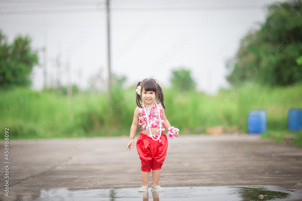 Naklejka premium Close-up background view of a blurred Asian girl running or teasing in the street in front of the house, doing activities together outside the classroom during the holidays.