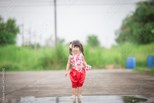 Close-up background view of a blurred Asian girl running or teasing in the street in front of the house, doing activities together outside the classroom during the holidays. © bangprik