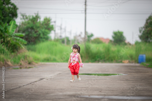 Close-up background view of a blurred Asian girl running or teasing in the street in front of the house, doing activities together outside the classroom during the holidays.