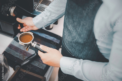Barista holding pressed ground coffee making espresso with machine