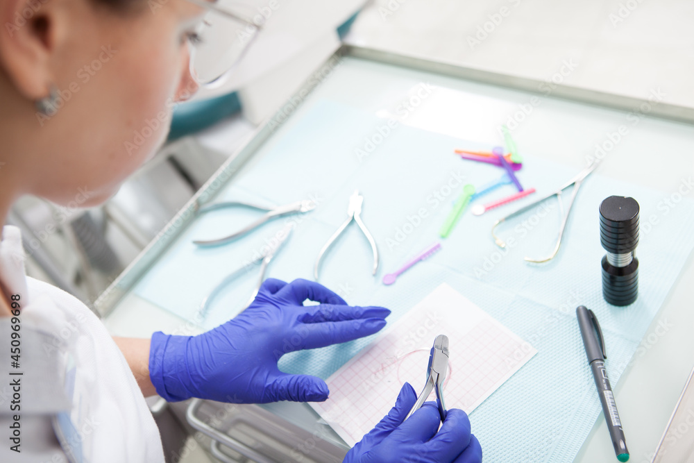 Cropped shot of a professional orthodontist preparing instruments to apply braces on teeth of patient Cropped shot of a professional orthodontist preparing instruments to apply braces on teeth of patient