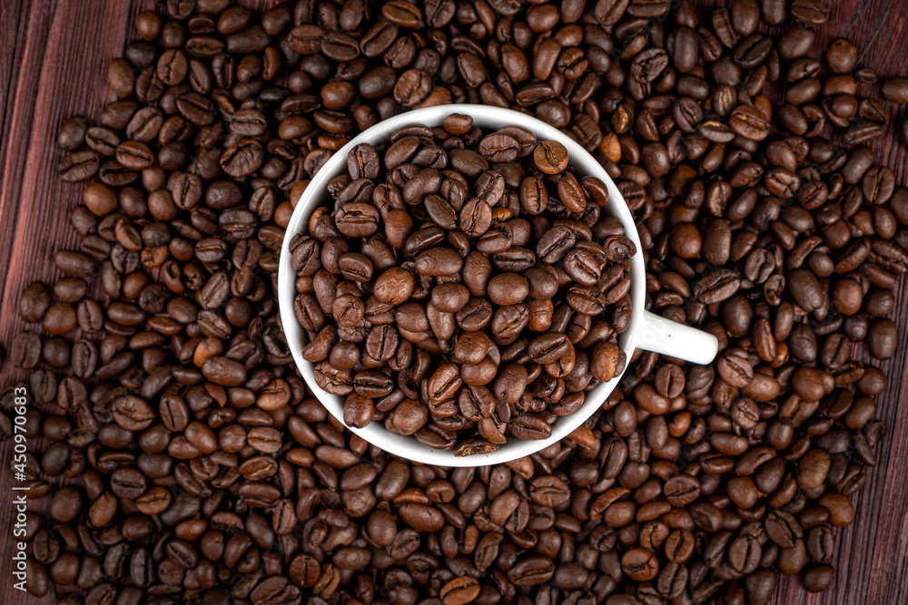 Scattered on the table beans of roasted coffee in a white cup. Morning. Cheerfulness Scattered on the table beans of roasted coffee in a white cup. Morning. Cheerfulness
