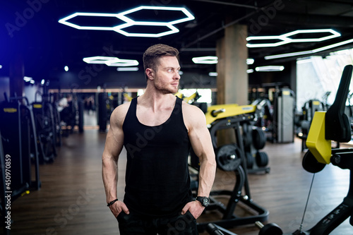 Athlete workout muscular trainer. Handsome young trainer posing for camera in gym.
