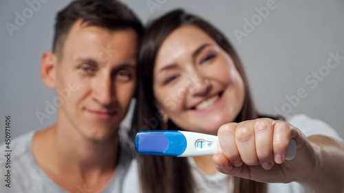 close-up of positive pregnancy test on blurred background of happy man and woman.