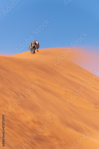 Positive attitude towards life. People walking on the sand dunes. Namibia, Africa.
