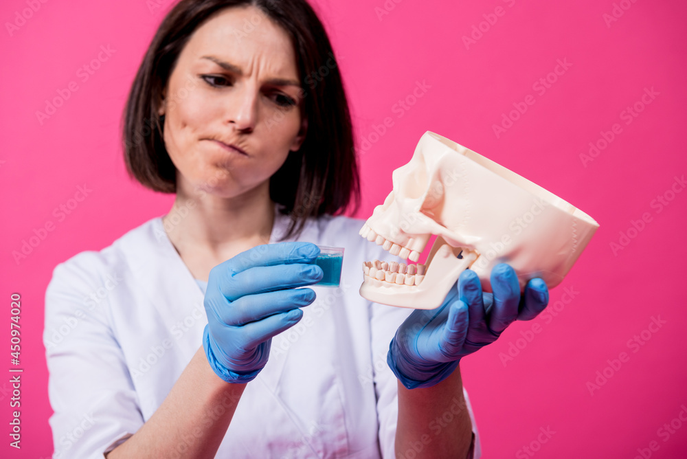 Beautiful girl proposes mouthwash for artificial skull Beautiful girl proposes mouthwash for artificial skull