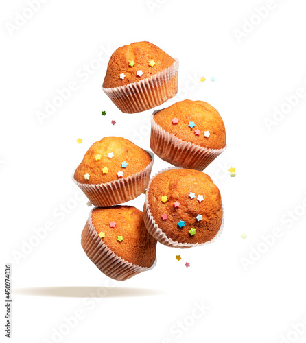 Fly delicious vanilla cupcakes. Cupcakes in paper liners with colorful icing stars fly isolated on white background.