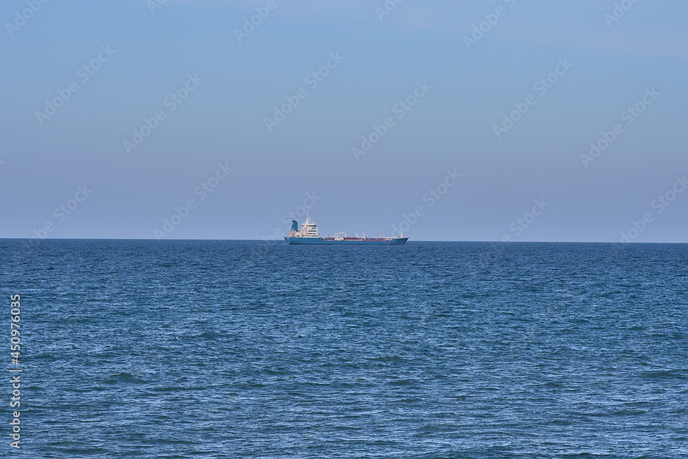 Beautiful evening view of cargo ship in the Irish Sea seen from West Pier of Dun Laoghaire harbor, Dublin, Ireland. Soft and selective focus. Minimalism
