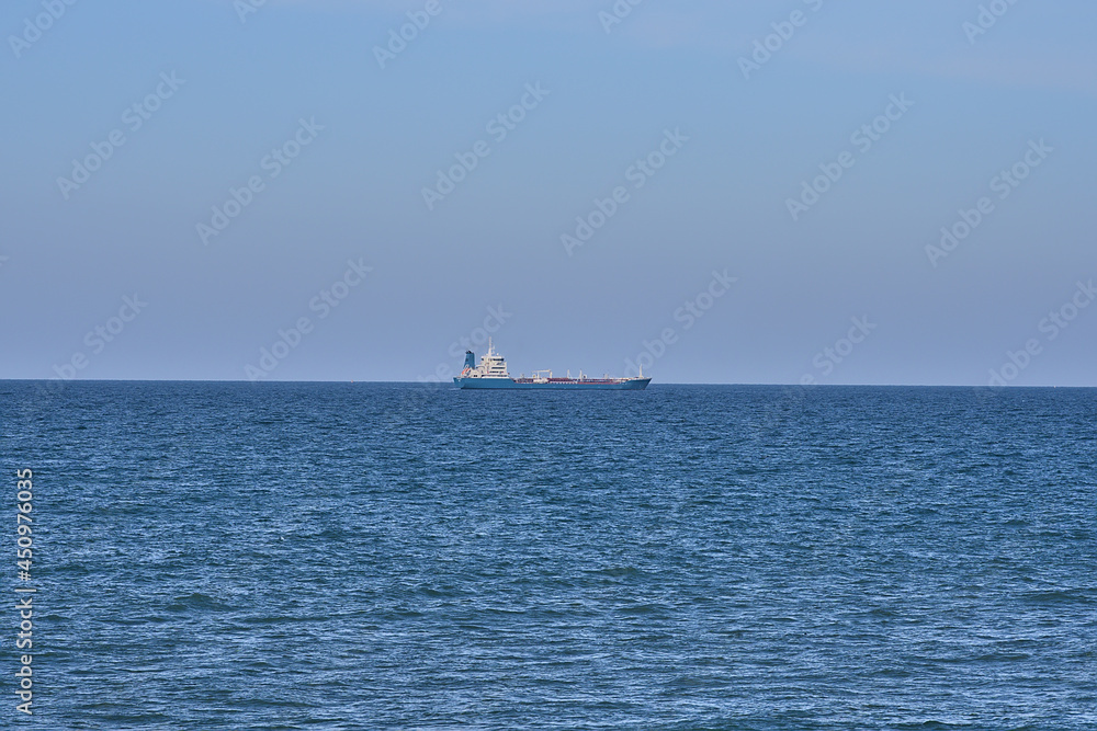 Beautiful evening view of cargo ship in the Irish Sea seen from West Pier of Dun Laoghaire harbor, Dublin, Ireland. Soft and selective focus. Minimalism Beautiful evening view of cargo ship in the Irish Sea seen from West Pier of Dun Laoghaire harbor, Dublin, Ireland. Soft and selective focus. Minimalism