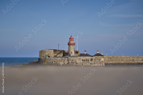 Beautiful creative evening view of red East Pier lighthouse in Dun Laoghaire harbor seen from West Pier, Dublin, Ireland. Copy space. Soft and selective focus