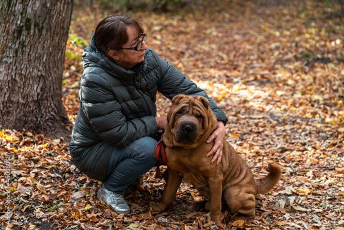 woman hugs her dog in a grove against a background of autumn trees