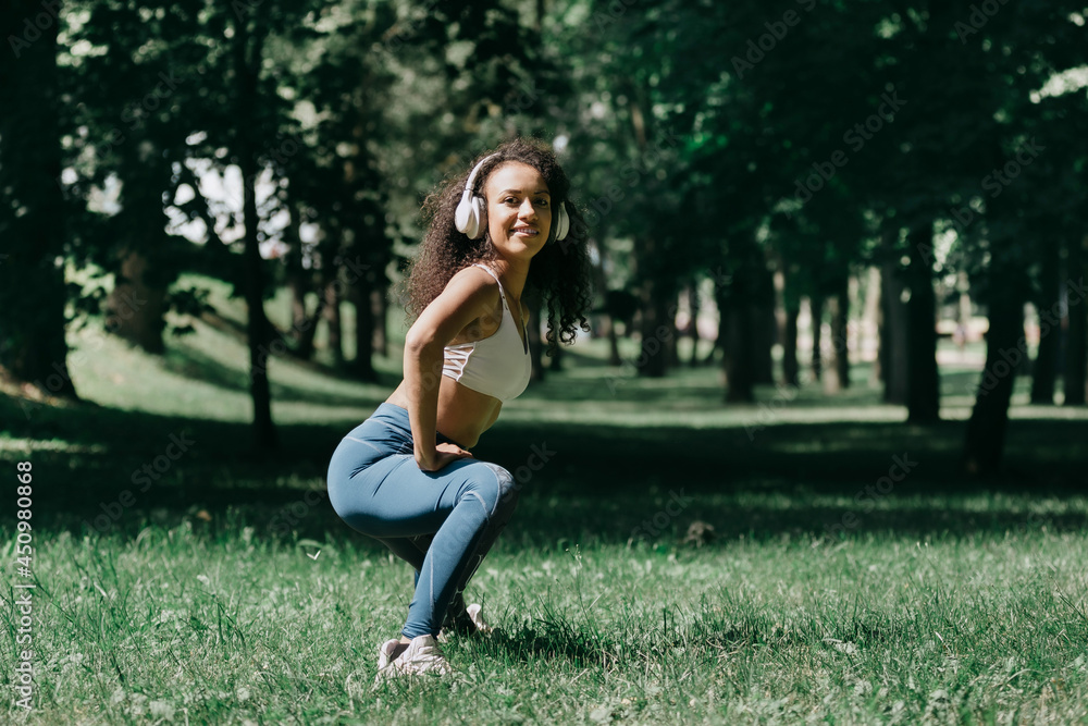smiling young woman does morning exercises in the park. smiling young woman does morning exercises in the park.