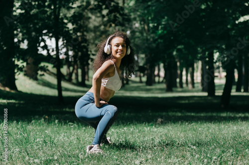 smiling young woman does morning exercises in the park.