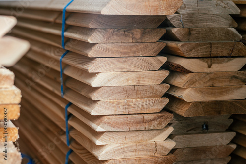 View of ends of stacked edged larch boards with beveled edge, planken for construction of fence or cladding house photo