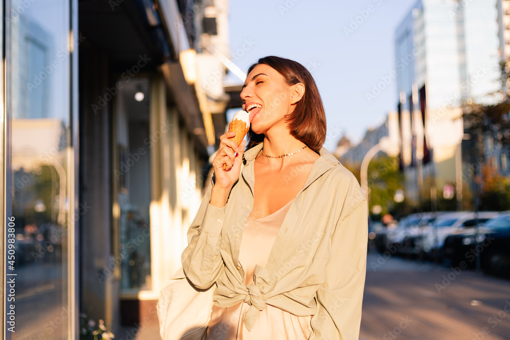 Woman outdoor at summer sunset time having ice cream cone positive happy playful at city street Woman outdoor at summer sunset time having ice cream cone positive happy playful at city street