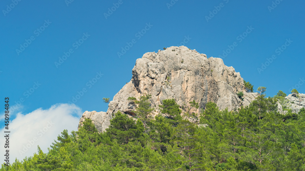 Turkish mountain with flag on top and trees in the area in the daytime Turkish mountain with flag on top and trees in the area in the daytime