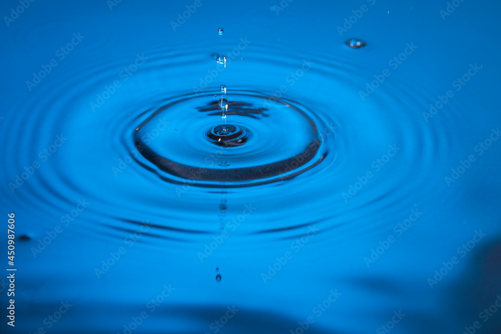 Beautiful view of drops making circles on blue water surface isolated on blue background. Beautiful view of drops making circles on blue water surface isolated on blue background.