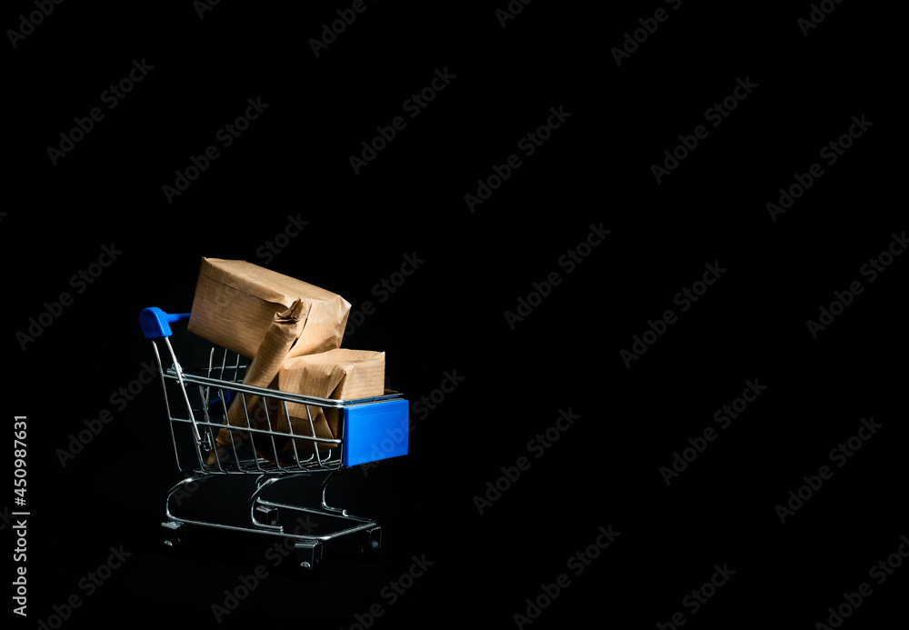 Shopping cart with boxes in brow wrapping paper ready for shipping. Isolated on black background.