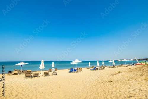 Beautiful landscape view of empty sunbeds and umbrellas on sand beach. Greece. © Alex