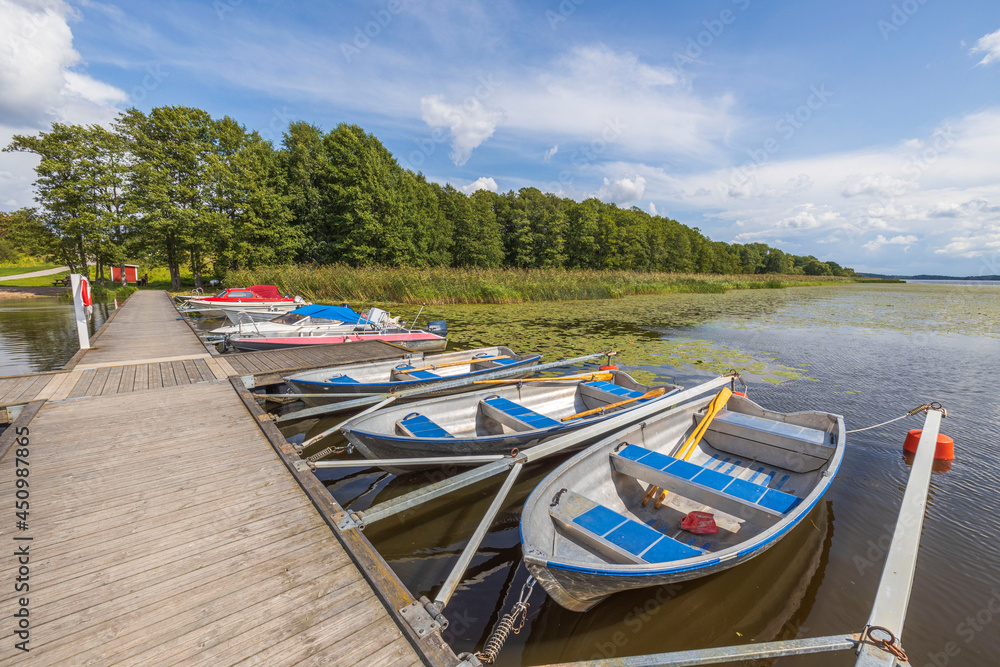 Naklejka premium Beautiful view of lake with boats parked in shore on blue sky background. Sweden.
