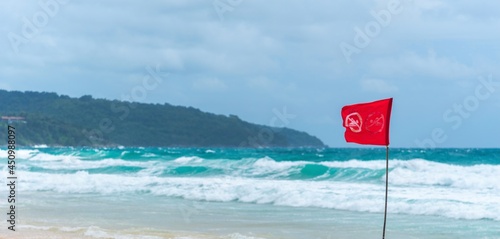 Red flag no swimming here sign at beach in windy day.