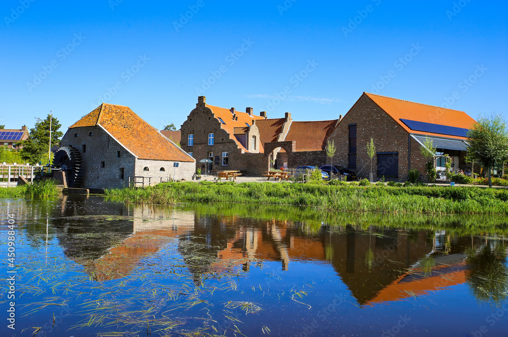 View over reflecting river pond on old water mill restaurant against deep blue cloudless summer sky - Neer (Limburg), Netherlands View over reflecting river pond on old water mill restaurant against deep blue cloudless summer sky - Neer (Limburg), Netherlands