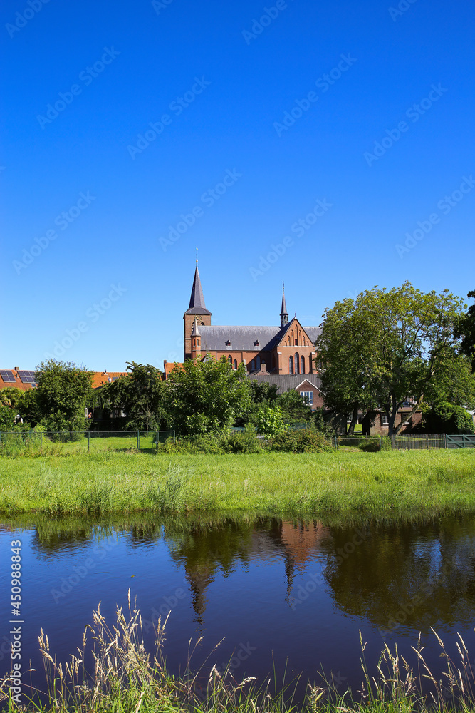 View over river and green pasture on small dutch idyllic village with medieval old church against blue cloudless summer sky - Neer (Limburg), Netherlands View over river and green pasture on small dutch idyllic village with medieval old church against blue cloudless summer sky - Neer (Limburg), Netherlands