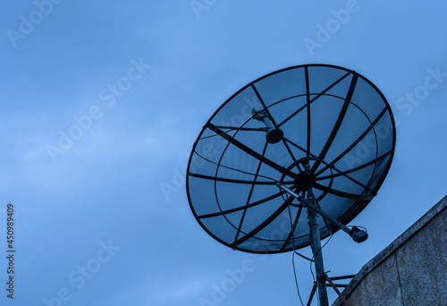 Satellite dish at the house roof in blue sky.
