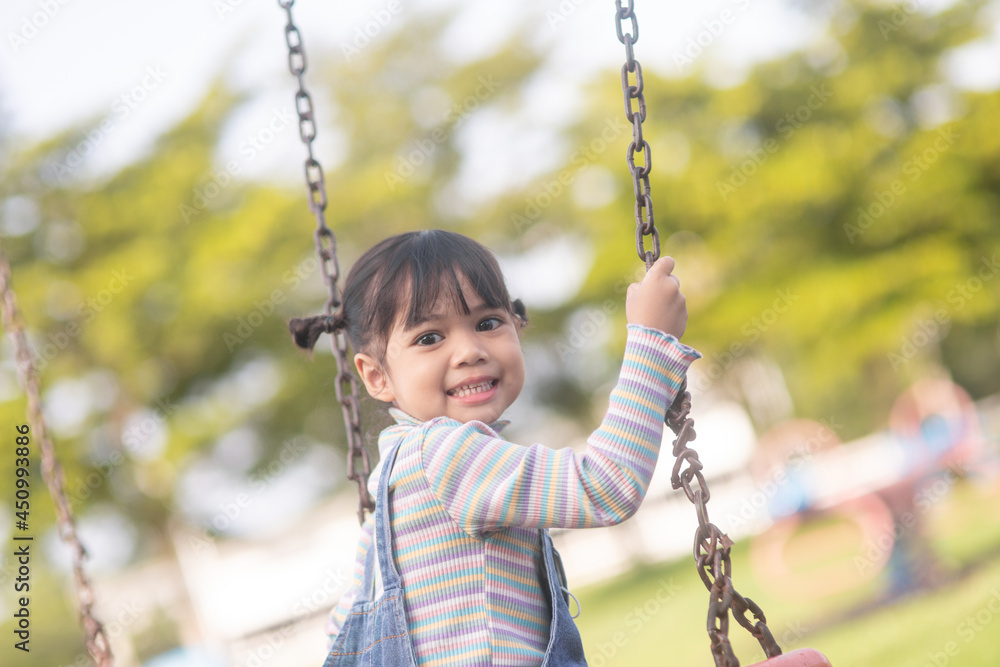 Happy little Asian girl playing swing outdoor in the park Happy little Asian girl playing swing outdoor in the park