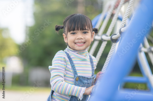 Cute children. Asian girl climbing in a rope playground structure at the adventure park