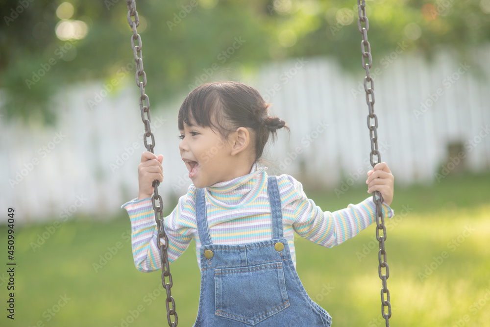Happy little Asian girl playing swing outdoor in the park Happy little Asian girl playing swing outdoor in the park