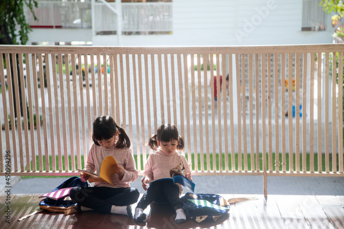 Cute Asian siblings girl reading a book at home.