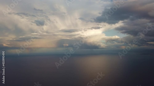 Clouds and ocean in the window plane. Cumulus clouds and sea fly by, illuminated by the sun. View of clouds and sea from above from the plane.