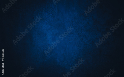 Dark blue textured concrete background with center light spot . Abstract texture for graphic design or wallpaper