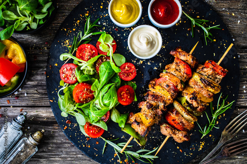 Skewers - grilled meat with fresh vegetables on wooden background 