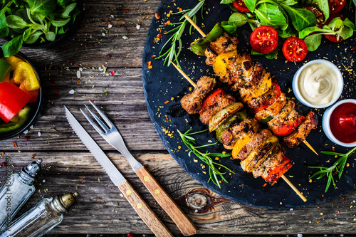 Skewers - grilled meat with fresh vegetables on wooden background 