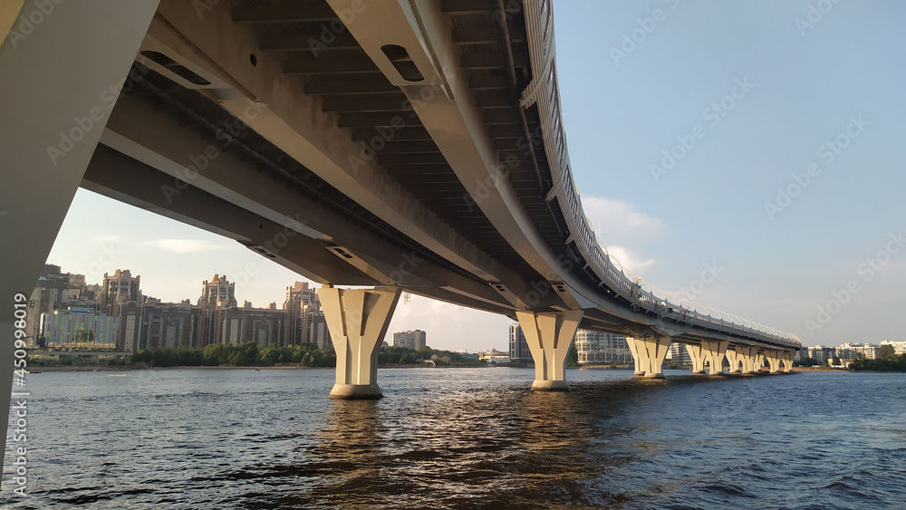 A modern flyover over the waterfront at the bay in the evening. Highway, a highway on the second level in a large city.