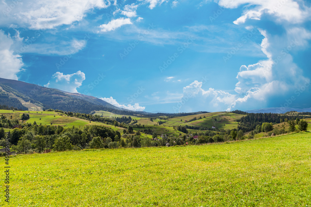 beautiful glade covered with grass on a background of mountains covered with forest and a beautiful sky with clouds. fabulous landscape.