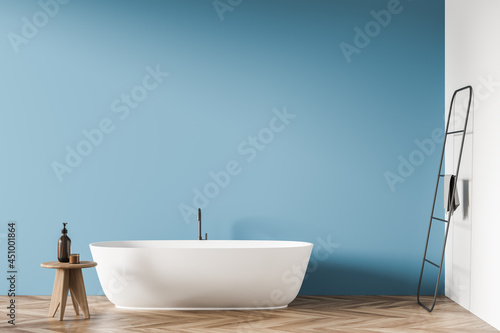 Oval white ceramic bathtub with minimalist design in blue bathroom background