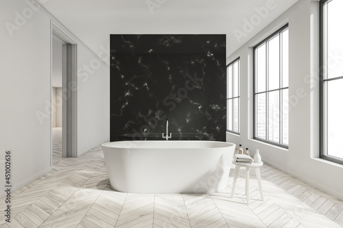 White bathroom space with black partition  walkways and ceramic bathtub