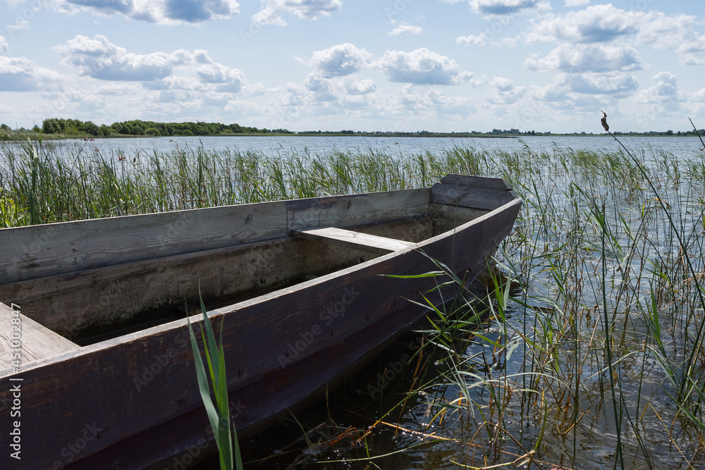 Old rural wooden, fishing boat moored in the shallow waters of the lake Old rural wooden, fishing boat moored in the shallow waters of the lake