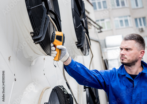 Technician uses a thermal imaging infrared thermometer to check the condensing unit heat exchanger.