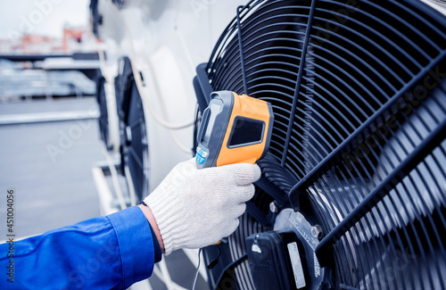 Technician uses a thermal imaging infrared thermometer to check the condensing unit heat exchanger.