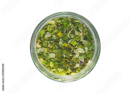 Dried green onions in a round transparent glass jar. View from above. Isolated on white background.