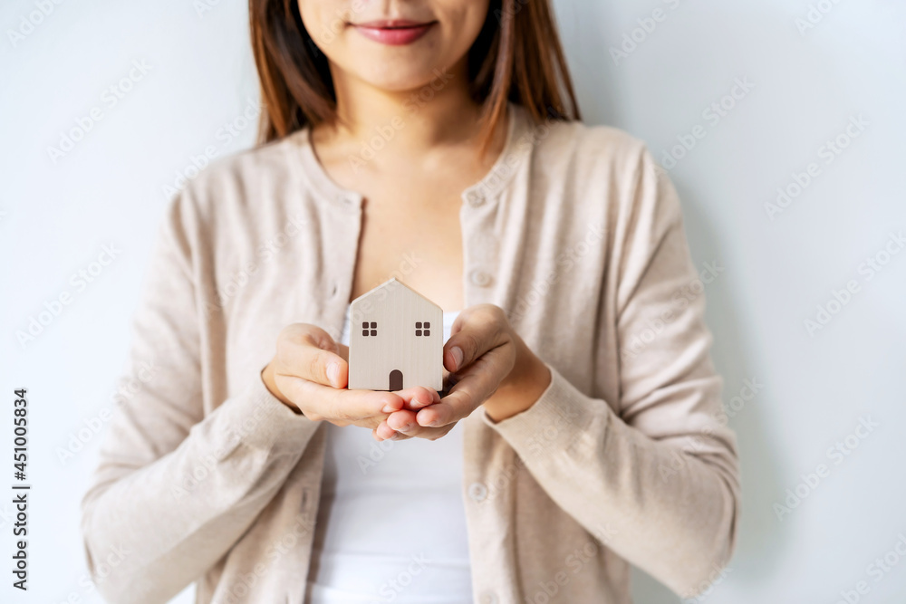 Hand of young woman holding wooden house model, Real estate concept Hand of young woman holding wooden house model, Real estate concept