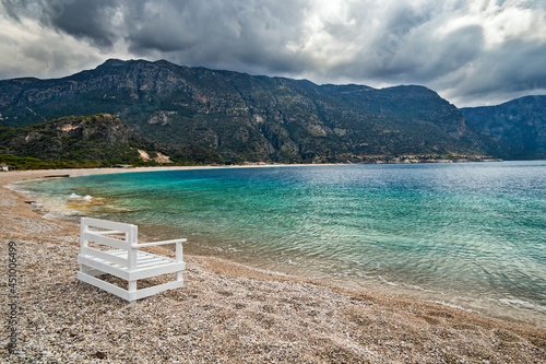Empty Oludeniz beach out of season on the background of the mountains in pre-thunderstorm weather. Mugla, Turkey.