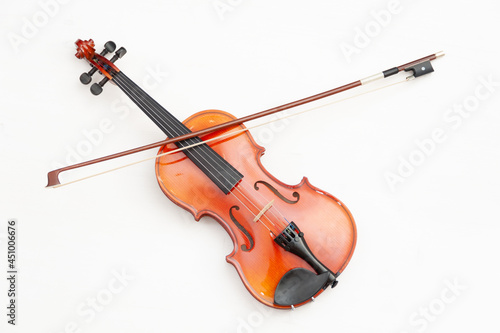 A violin with a bow on a white wooden background. A musical stringed instrument.